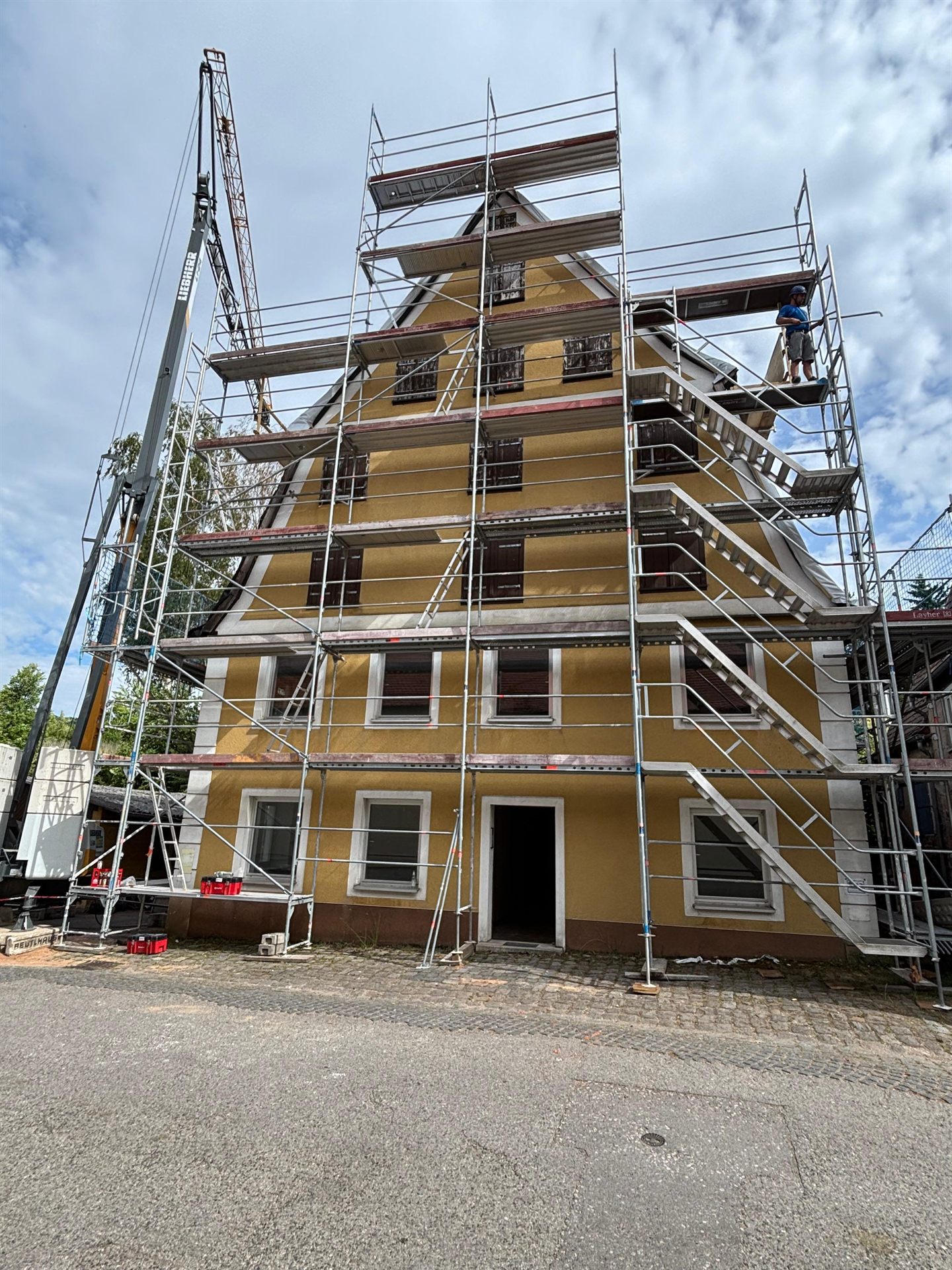 Eingerüstetes Mehrfamilienhaus mit Kran